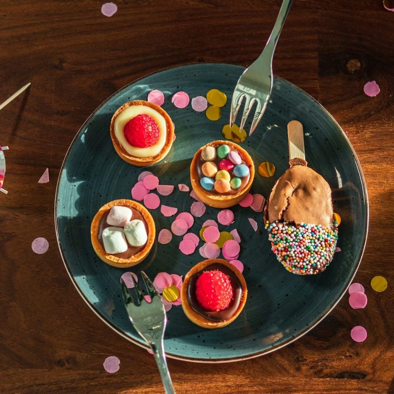 Delicious Home-cooked Party Treats A plate full of colourful cakes surrounded by confetti.